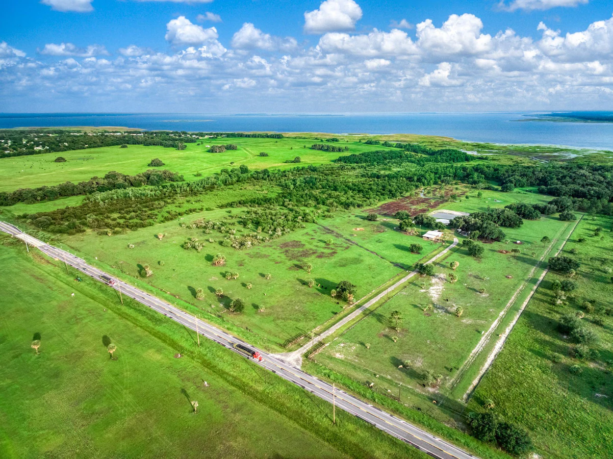 Aerial view of land bordered by roads, with a lake in the distance.