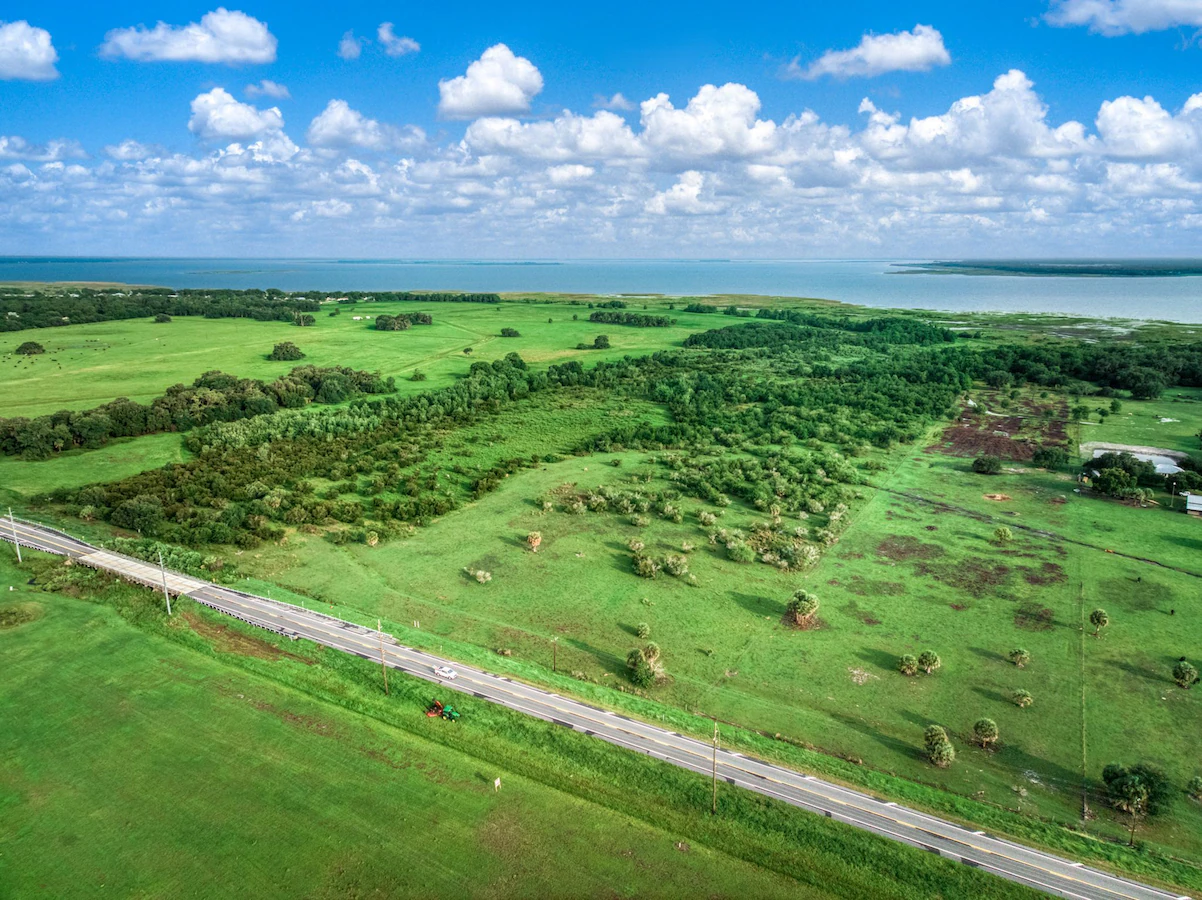 Aerial view of open land, woodland, and a road.